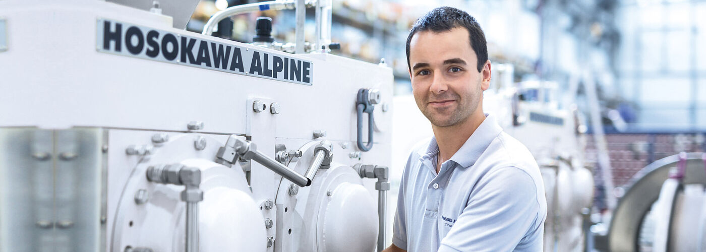 Hosokawa Alpine employee stands next to a compactor