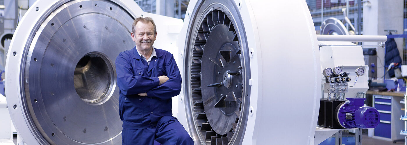 A Hosokawa Alpine employee standing with crossed arms in front of the Ultraplex UPZ fine impact mill.