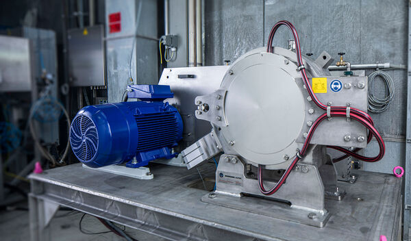 A grey Hosokawa classifier mill named Alpine Particle Rounder with a blue motor, standing on a metal table in a workshop