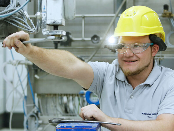 A Hosokawa Alpine employee performing maintenance on a machine.