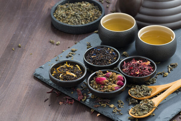 Various ground teas in small, black bowls on a black plate