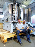 Two men sitting in front of a Polyplex machine