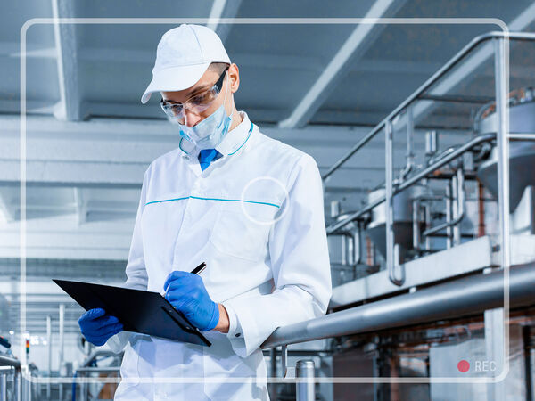 A worker preparing documentation on a clipboard in a factory hall.